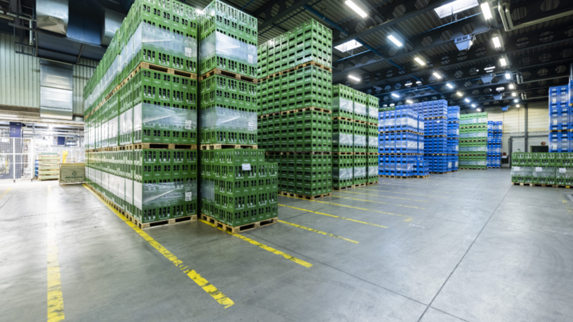 Vaste entrepôt de boissons de Heineken avec des caisses réutilisables empilées sur des palettes pour la distribution