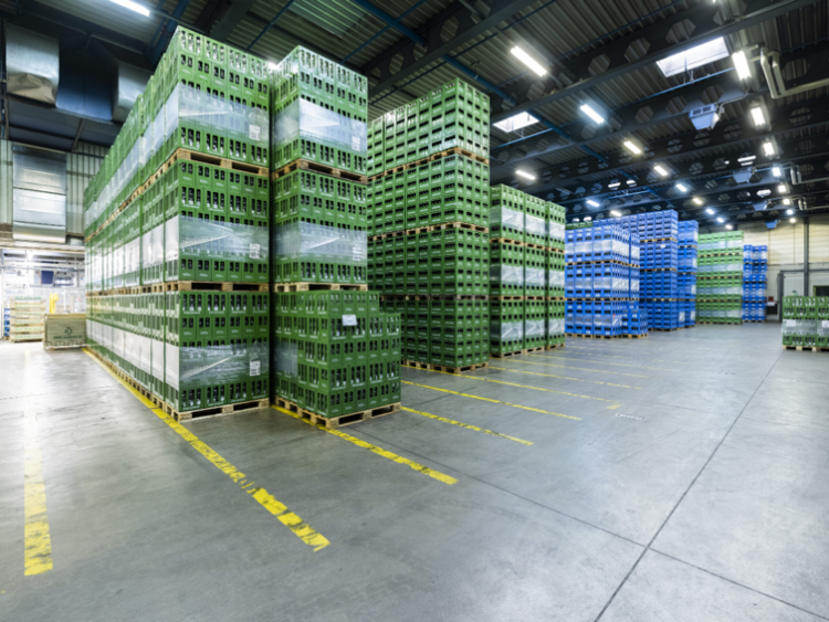 Vaste entrepôt de boissons de Heineken avec des caisses réutilisables empilées sur des palettes pour la distribution