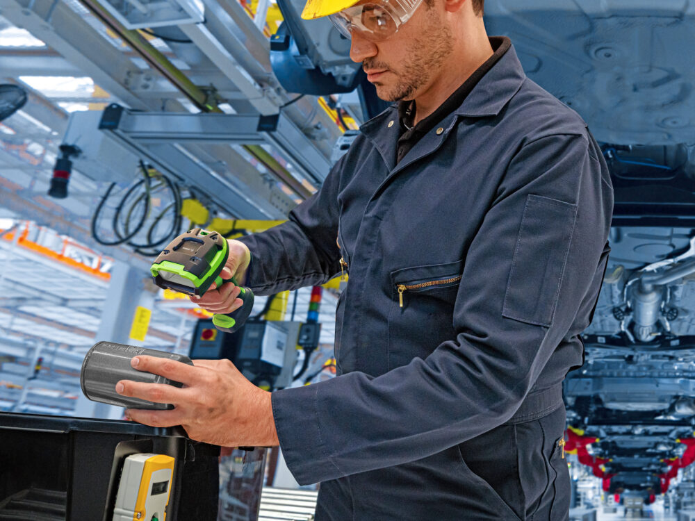 Opérateur industriel scanne des pièces avec lecteur de codes-barres robuste pour assurer la traçabilité