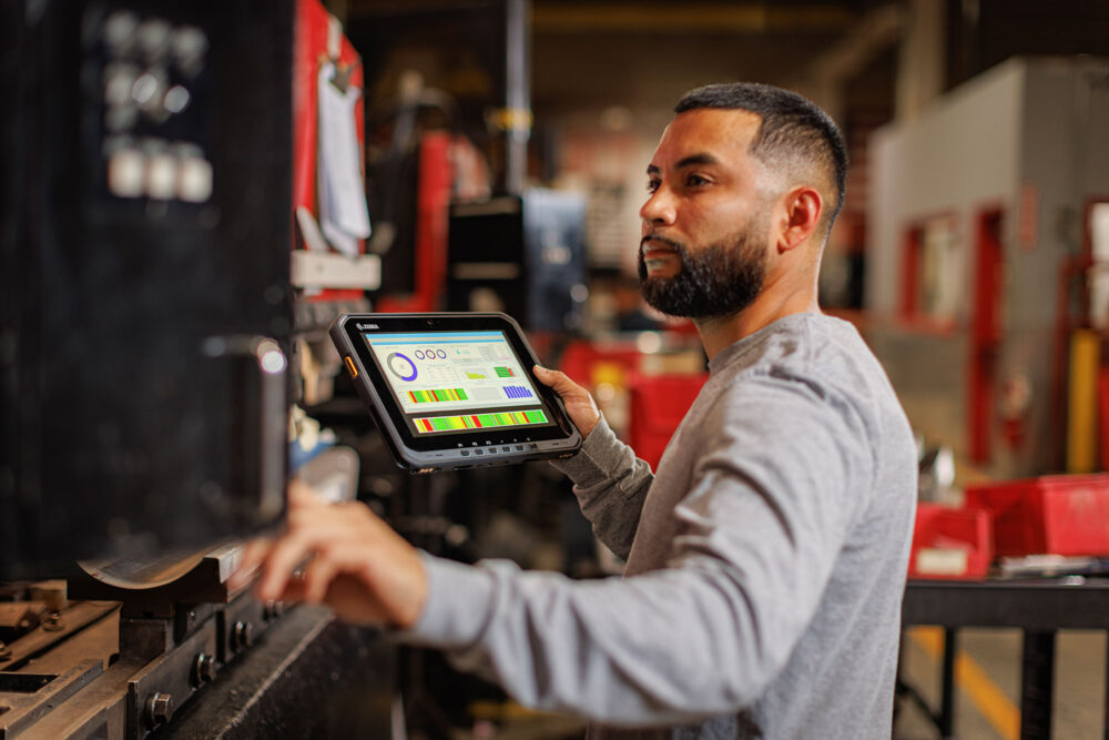 Industriearbeiter nutzt robustes Tablet zur mobilen Datenerfassung an Produktionsmaschine