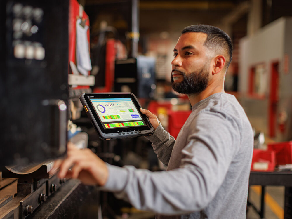 Opérateur industriel utilisant une tablette durcie pour saisir des données sur une machine