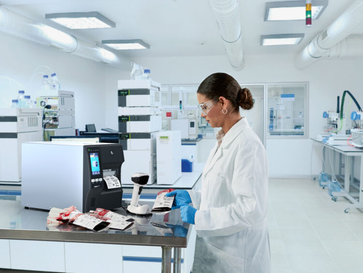 Une technicienne de laboratoire étiquette les conserves de sang avec des étiquettes à code-barres dans les processus hospitaliers numériques