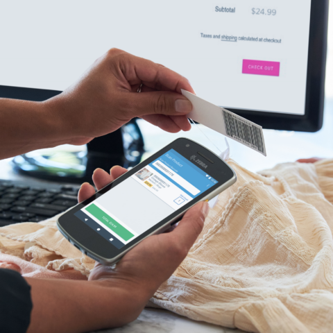 Verkäuferin in einem Einzelhandelsgeschäft scannt das Preisschild eines Kleidungsstücks mit einem mobilen Terminal