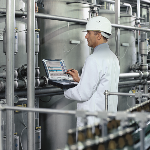 Ingenieur nutzt ein robustes Panasonic Toughbook Notebook in einer Produktionsanlage für die digitale Prozessüberwachung, mobile Datenerfassung zur Qualitätssicherung und papierlose Protokollierung der Inspektion