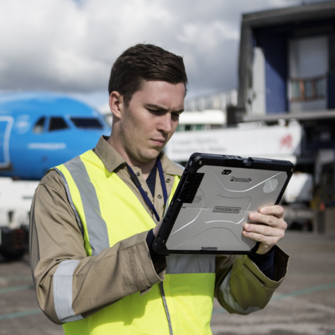 Flughafenmitarbeiter nutzt ein Panasonic Toughbook Tablet mit lichtstarkem Bildschirm für die mobile Erfassung von Daten und Aufgaben rund um die Bodenabfertigung auf dem Rollfeld