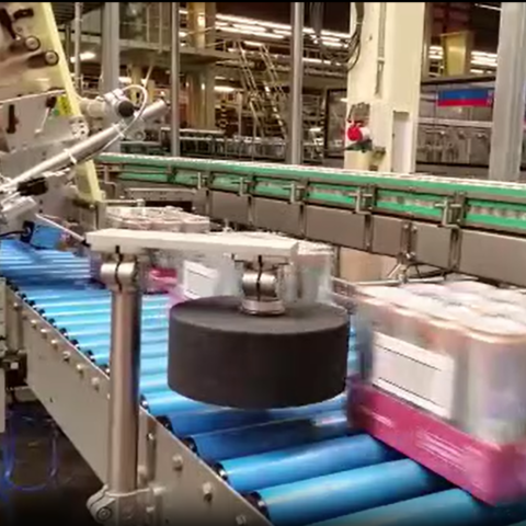 Automatischer Etikettierer kennzeichnet Getränkepackungen auf einer Förderanlage in einer Hochgeschwindigkeits-Produktionslinie