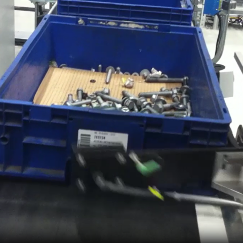 Automatischer Etikettenapplikator kennzeichnet eine Teilebox auf einem Förderband mit einem Barcode-Etikett