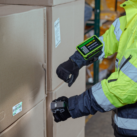 Lagerarbeiter in Tieftemperaturumgebung scannt ein Barcode-Etikett mit einem Wearable System bestehend aus mobilem Terminal und Handrückenscanner