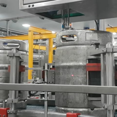 Automatische Etikettieranlage in einer Bierbrauerei kennzeichnet Edelstahlfässer mit Barcode-Etiketten