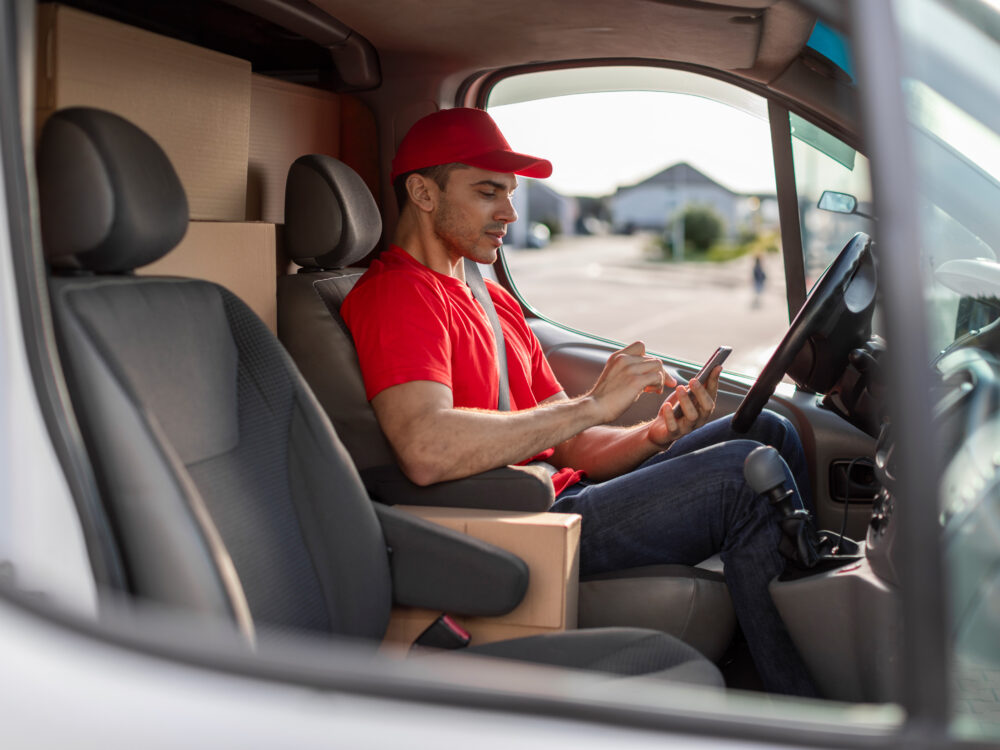 Kurierfahrer einer Speditionsfirma erhält Informationen über die Transportroute und erfasst Informationen über Lieferungen und Retouren auf einem mobilen Terminal