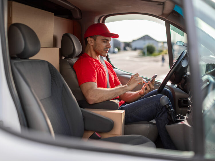 Livreur travaillant pour une entreprise de transport reçoit des informations sur l'itinéraire et saisit les données relatives aux livraisons et aux retours sur un terminal mobile